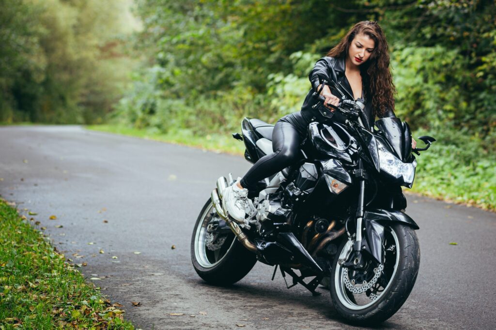 Portrait of a beautiful young woman sitting on a motorcycle, riding a motorcycle in black leather